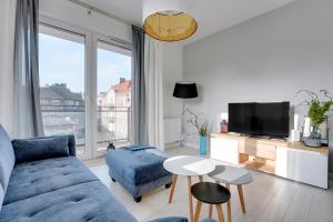 een woonkamer met een blauwe bank en een tv bij NORDBYHUS Apartamenty Nowa Grobla in Gdańsk