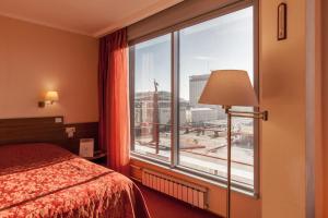 ein Hotelzimmer mit einem Bett und einem großen Fenster in der Unterkunft Eurootel Stavropol in Stawropol