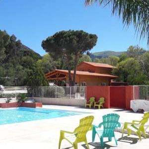 ein Pool mit gelben und grünen Stühlen und ein Haus in der Unterkunft Camping le Rancho in Argelès-sur-Mer