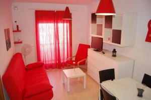 uma sala de estar com mobiliário vermelho e uma cadeira vermelha em Apartamentos y Áticos Zahara em Zahara de los Atunes