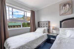 a bedroom with two beds and a window at Kingfisher Hollow in Gordonʼs Bay