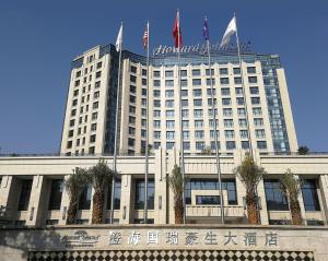 a large building with flags on top of it at Howard Johnson Glory Plaza Chenghai in Shantou