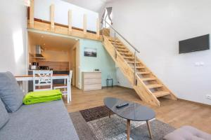 een woonkamer met een bank en een trap bij Domaine des Ecuries - Appartements meublés à Talloires in Talloires