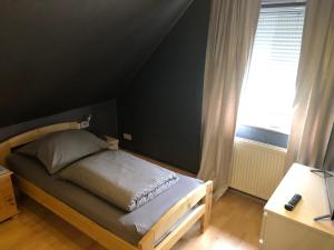 a small bed in a room with a window at Messe Apartment & Rooms Hänigsen in Hänigsen