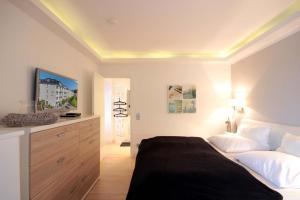 1 dormitorio con 1 cama y vestidor con TV en Villa Allegra by Rujana en Binz
