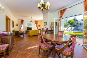 een woonkamer met een houten tafel en stoelen bij Villa Amarela in Boliqueime