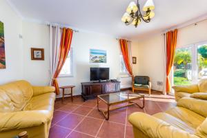 een woonkamer met banken en een tv bij Villa Amarela in Boliqueime