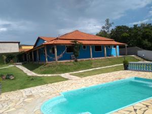 Villa con piscina frente a una casa en Chácara Recanto dos Pássaros, en São Thomé das Letras