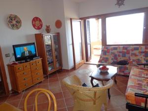 un soggiorno con TV, tavolo e sedie di Una terrazza in Paradiso a Costa Paradiso