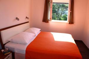 a bedroom with a bed with an orange blanket and a window at Gorgonia Suites in Verunic in Verunić