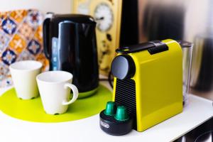 a yellow coffee maker sitting on a counter with cups at Mi Rincon Central Apartment in Seville