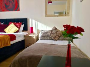 a red vase with red roses on a table in a bedroom at Studio Apartment, Private Bathroom and Parking in Ilford +13 photos