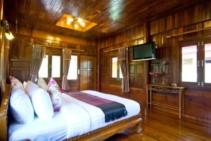 a bedroom with wooden walls and a bed with a tv at Bueng Bua Thong Resort in Ban Huai Yai