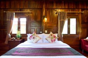 a bedroom with a bed with wooden walls and windows at Bueng Bua Thong Resort in Ban Huai Yai