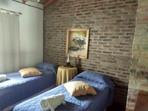 two beds in a room with a brick wall at Cabañas del Uru in Colón