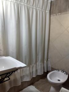 y baño con cortina de ducha y lavamanos. en Cabañas del Uru en Colón