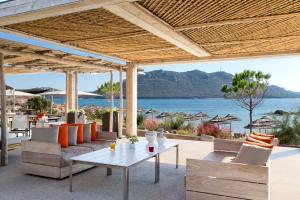 an outdoor patio with a table and chairs and the ocean at La Plage Casadelmar in Porto-Vecchio