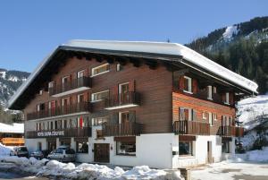 a large wooden building with snow on the ground at Hôtel Eliova l'Eau Vive in Châtel