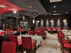 a dining room with tables and red chairs at Hotel-Restaurant Pfeffermühle Balingen in Balingen