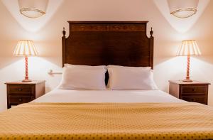 a bedroom with a large bed with two lamps at Casa Amarela TH & National Monument in Castelo de Vide