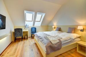 a bedroom with a bed and a desk and two windows at hotel Chmelnice in Napajedla