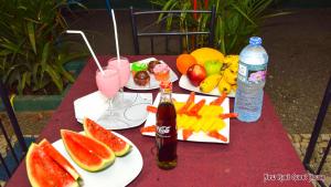 una mesa con dos platos de comida, bebida y fruta en New Rasi Guest House, en Dambulla