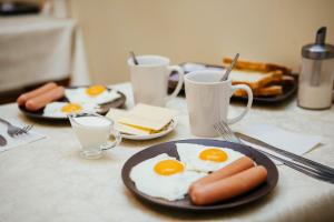 una mesa con platos de huevos, salchichas y tostadas en Апартаменты Sampo, en Víborg