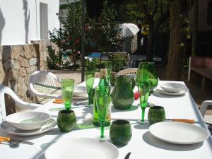 een witte tafel met groene glazen en borden erop bij CasasMontseny in Arbúcies