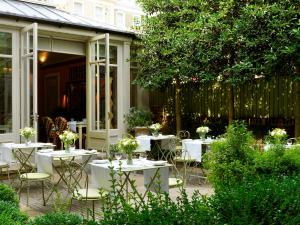 a patio with white tables and chairs and a fence at Number Sixteen, Firmdale Hotels in London +19 photos