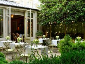 a patio with white tables and chairs and a fence at Number Sixteen, Firmdale Hotels in London