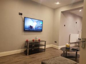 a living room with a flat screen tv on the wall at Monyhull Homestay - near City centre Kingsheath NIA NEC BHX in Birmingham