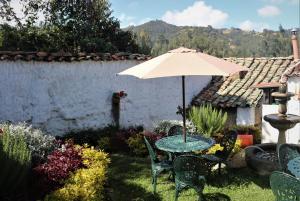 einen Tisch und Stühle mit Sonnenschirm im Hof in der Unterkunft Hotel Otti Colonial in Monguí