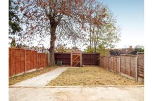 a fence with a tree in front of a building at Monyhull Homestay - near City centre Kingsheath NIA NEC BHX in Birmingham