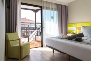 a bedroom with a bed and a chair and a balcony at Vanilla Garden Boutique Hotel - Adults Only in Playa de las Americas +37 photos