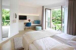 a white bedroom with a large bed and a desk at Boutique Hotel Reschen in Tutzing