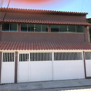 una casa con puertas blancas de garaje con techo rojo en CASA PÔR DO SOL 3, en Arraial do Cabo