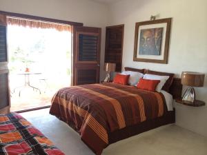 a bedroom with a bed with red pillows and a window at Hotel Maria Maria in Bacalar