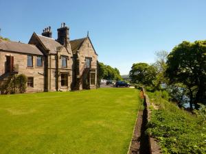 een oud huis met een groen gazon ervoor bij Castle Vale House in Berwick-Upon-Tweed