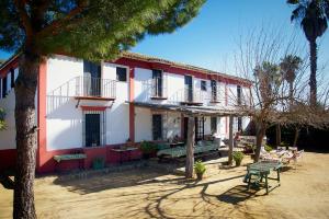 a red and white building with tables and benches at Hacienda de Santa Teresa in Almonte