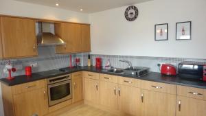 a kitchen with wooden cabinets and black counter tops at Plymouth Dockyard at Latitude 52 inc parking in Plymouth