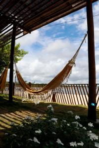 a hammock in a yard with a wooden fence at Pousada Pérola do Atlântico in Ilha de Boipeba