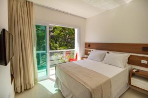 a bedroom with a bed and a large window at Apart-Hotel Bella Vida Suítes e Apartamentos in Morro de São Paulo