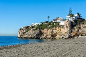 einen Strand mit einem Haus auf einer Klippe in der Unterkunft WintowinRentals Best Location, Beach, Pool & Parking in Rincón de la Victoria