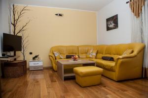 ein Wohnzimmer mit einem gelben Sofa und einem Tisch in der Unterkunft Apartmani Kanjer 1 Delnice in Delnice