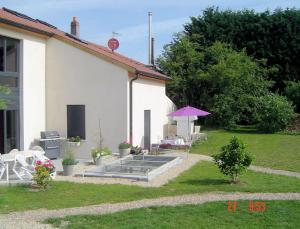 a house with a table and chairs and an umbrella at Aux Plumes de Grigy in Metz