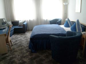 a hotel room with a bed and two chairs and a tv at Hotel Novalis in Berlin