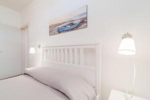 a white bedroom with a bed and a picture on the wall at Le Dimore di Luciana in Marina di Pescoluse