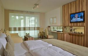 a bedroom with a bed and a tv on a wall at Parkhotel Oberhausen in Oberhausen