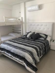 ein Schlafzimmer mit einem Bett mit einer gestreiften Decke in der Unterkunft Sashii Hostel & Boutique. in Ríohacha