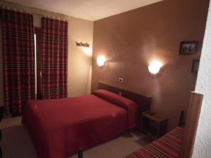 Habitación de hotel con 1 cama roja y 2 ventanas en Hostal La Muralla, en Morella